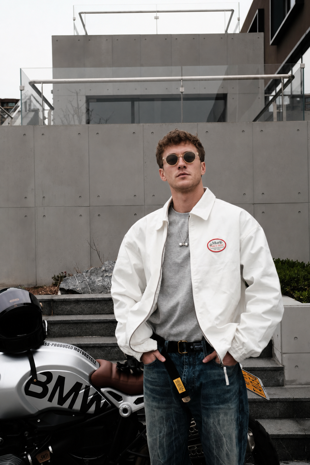 Young American male model wearing a silver dumbbell pendant necklace beside a motorcycle