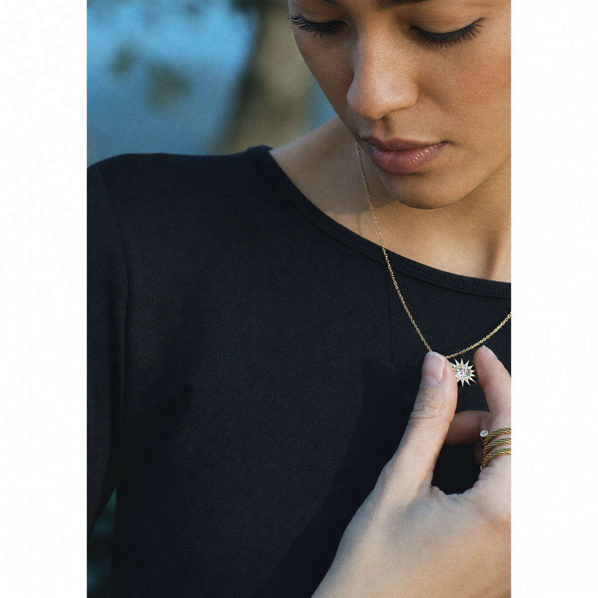 Close-up of Latina model holding gold Solstice Sun pendant necklace